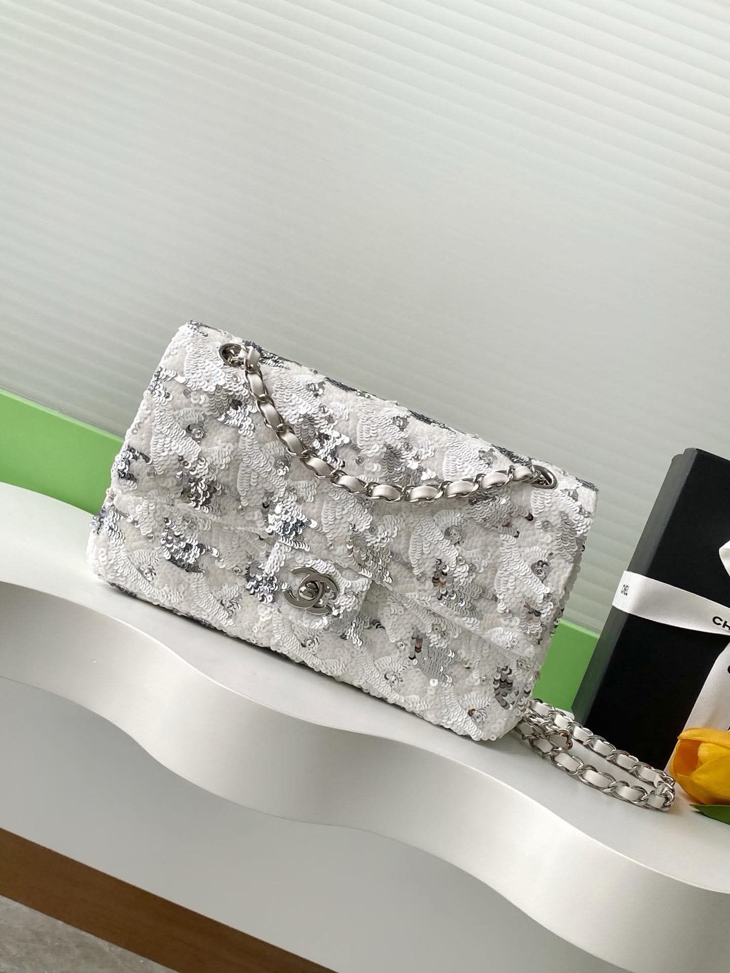 Silver glittery Sequen Channel handbag on a white surface 